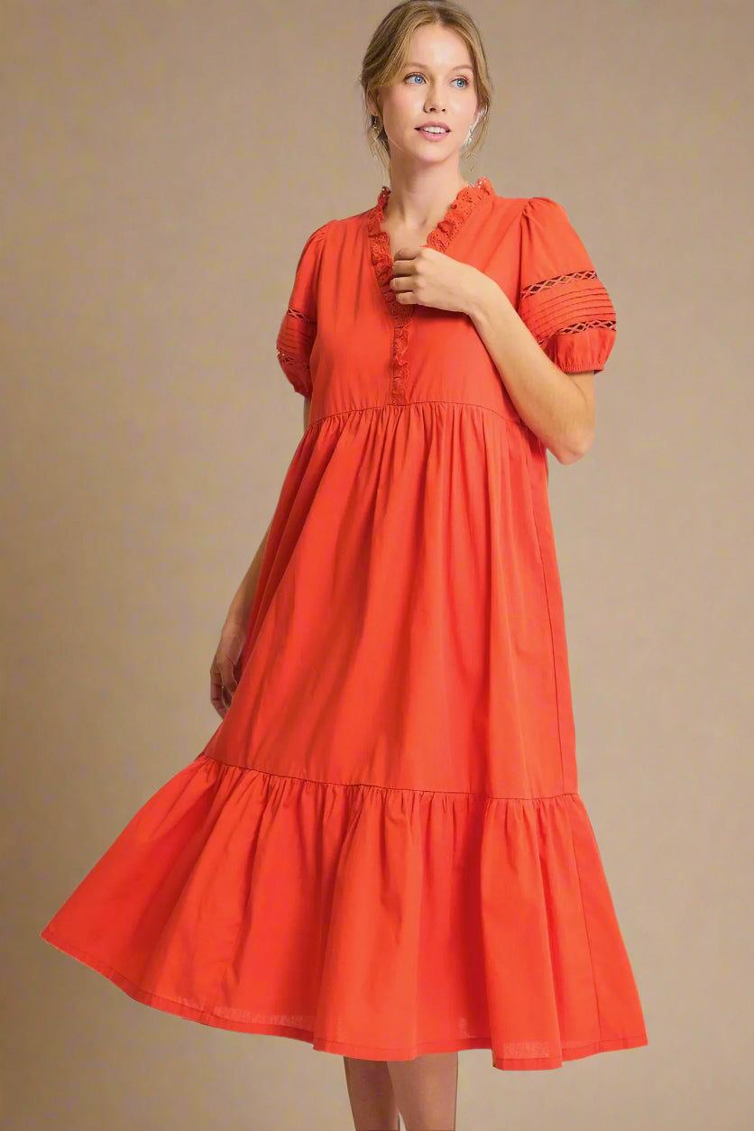 Woman wearing a tomato red dress with puff sleeves on a plain background