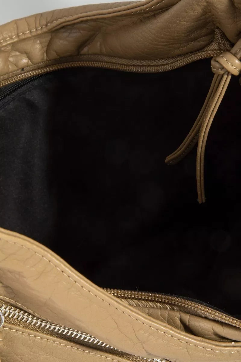Close-up of a beige leather bag with a zipper, showing the interior.