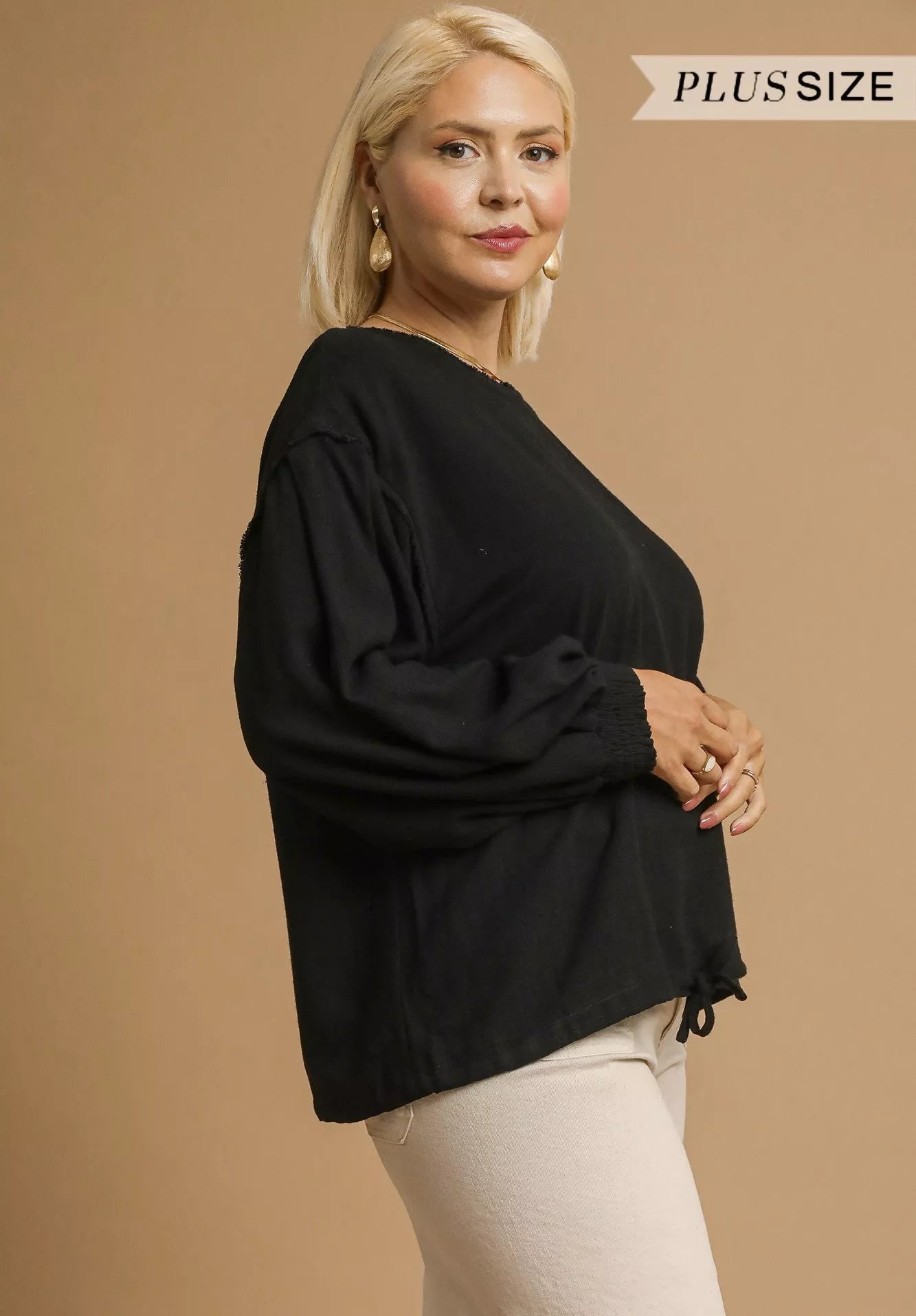 Woman wearing a black plus-size top against a beige background