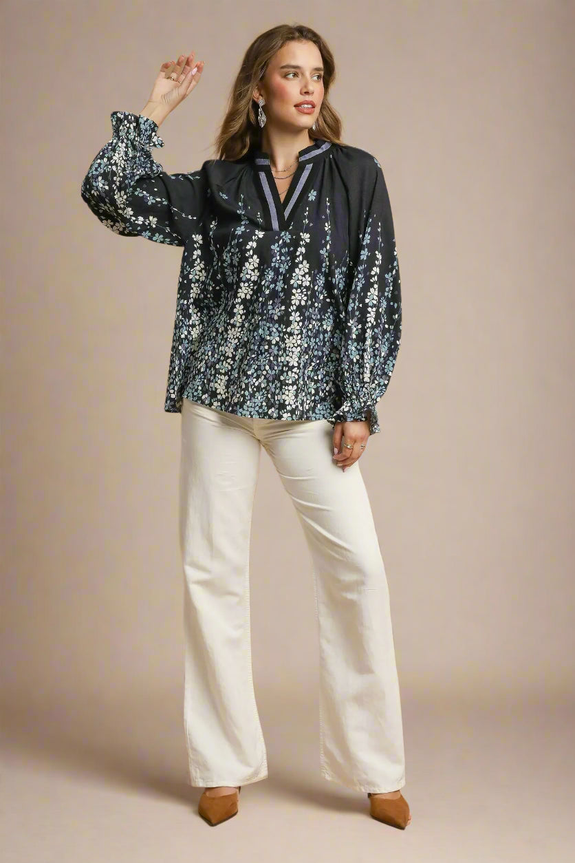 Woman wearing a floral blouse and white pants on a beige background