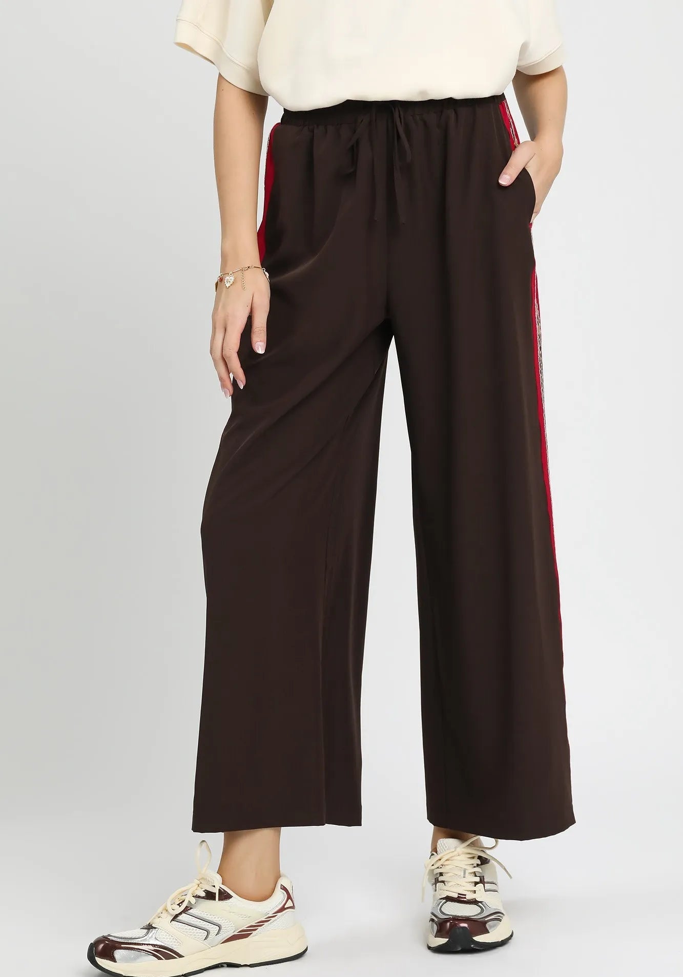 Brown wide-leg pants with red stripes on a gray background