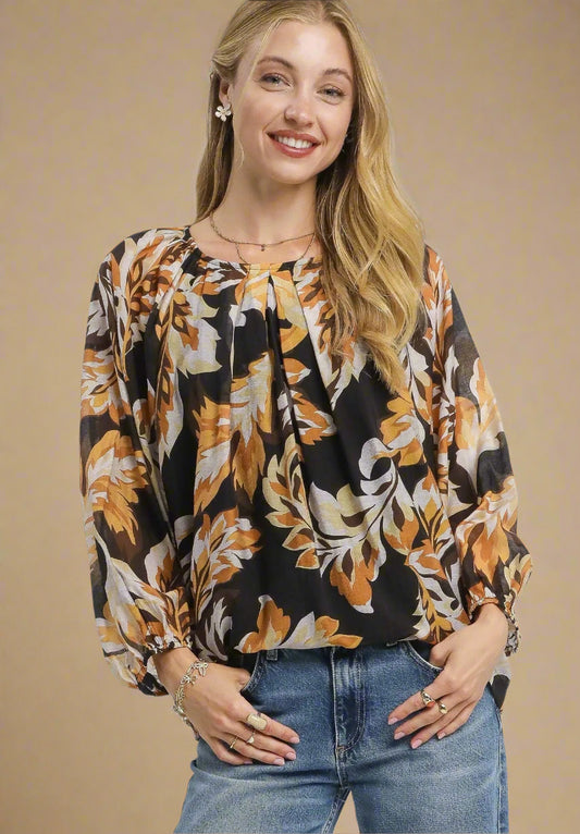Woman wearing a black floral blouse and blue jeans on a beige background