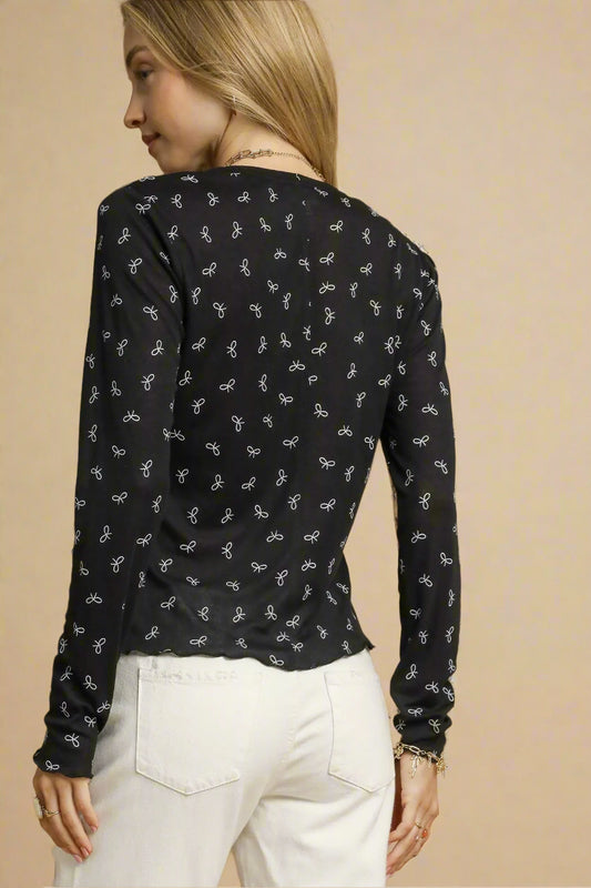 Woman wearing a black long-sleeve top with a subtle pattern on a beige background