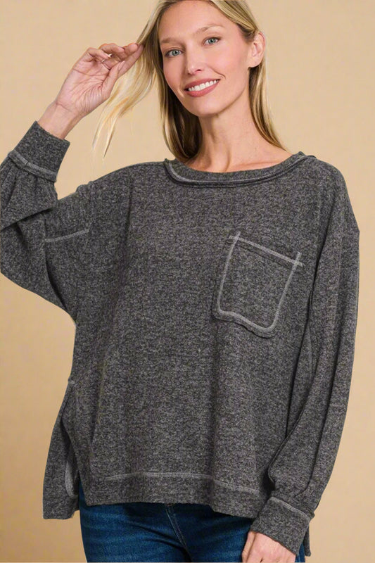 Woman wearing a gray sweater with a pocket on a beige background