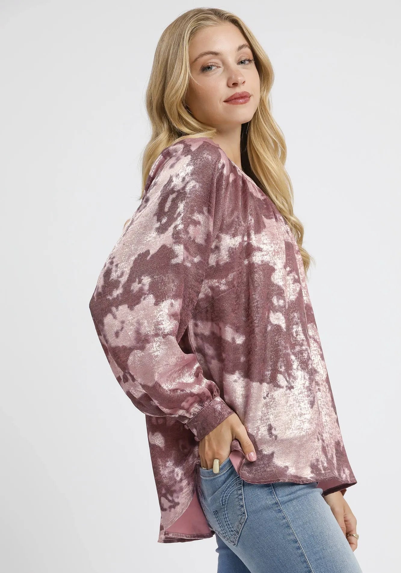 Woman wearing a tie-dye shirt and jeans on a white background