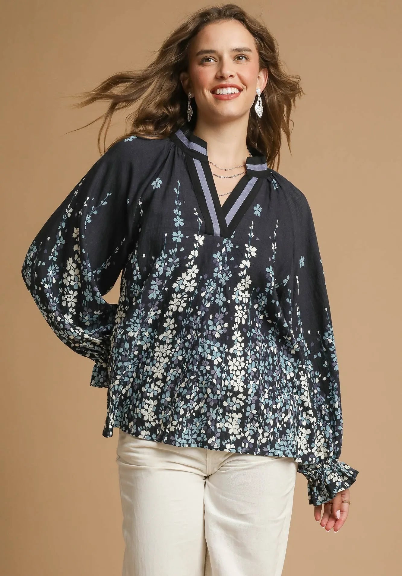 Woman wearing a black floral blouse against a beige background