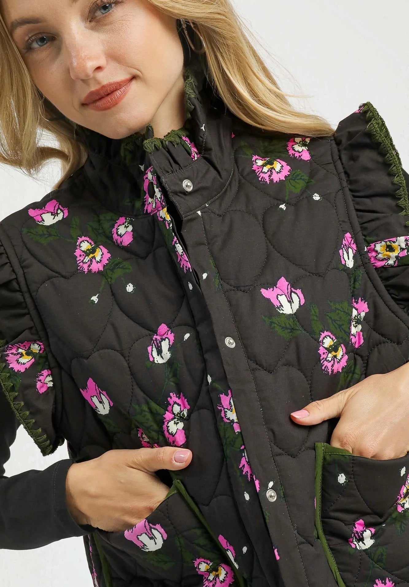 Woman wearing a black quilted vest with pink floral patterns on a white background