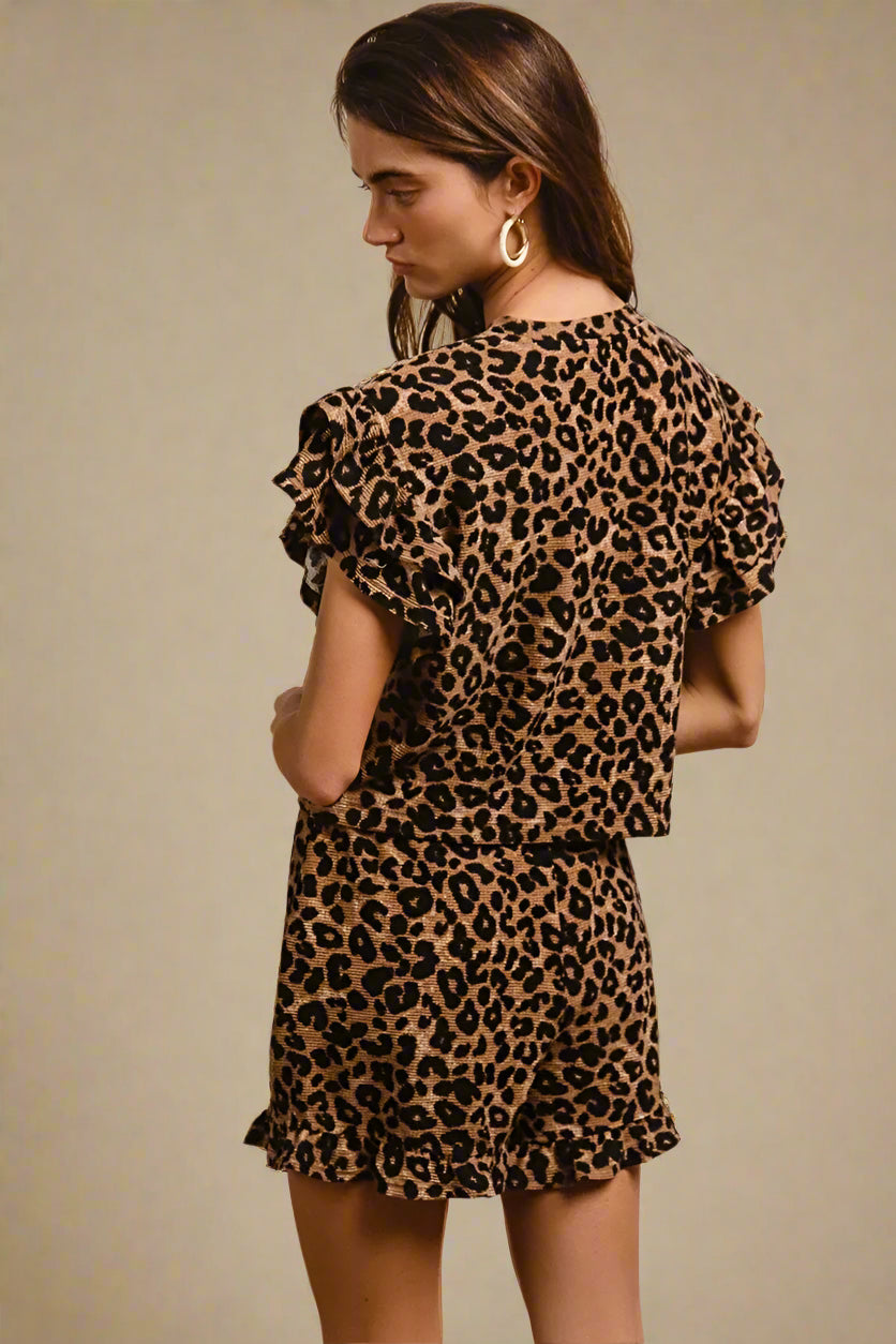 Woman wearing a leopard print shorts set against a beige background