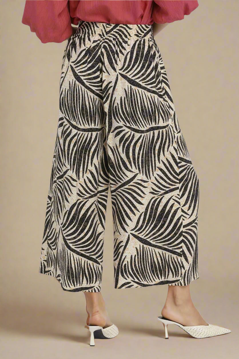 Person wearing a patterned wide-leg pants with a plain background