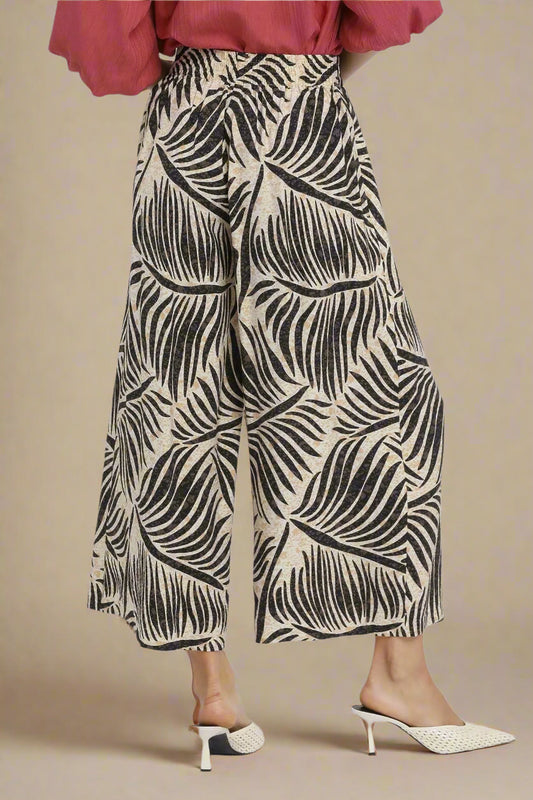 Person wearing a patterned wide-leg pants with a plain background