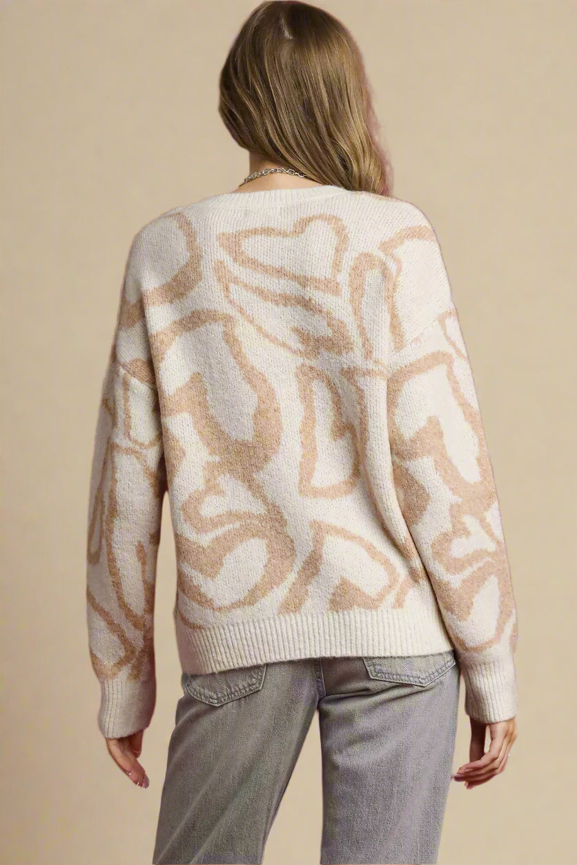 Person wearing a cream sweater with a pattern on a red background