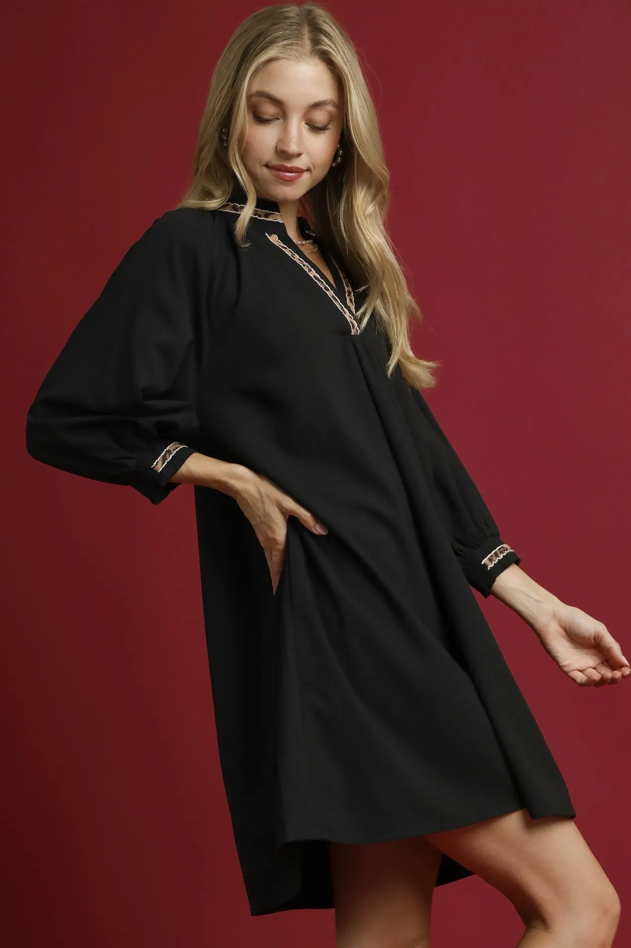 Woman wearing a black dress with gold trim on a red background