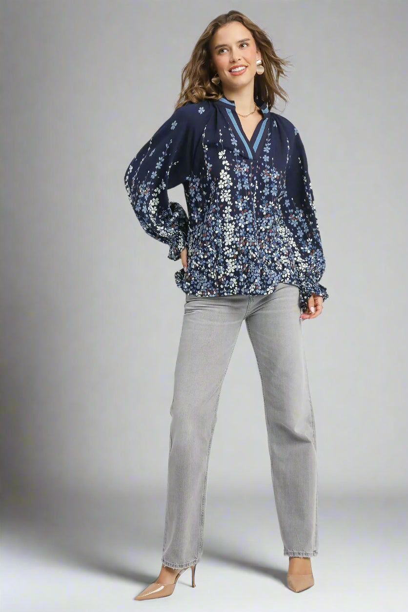 Woman wearing a navy floral blouse and gray pants on a white background