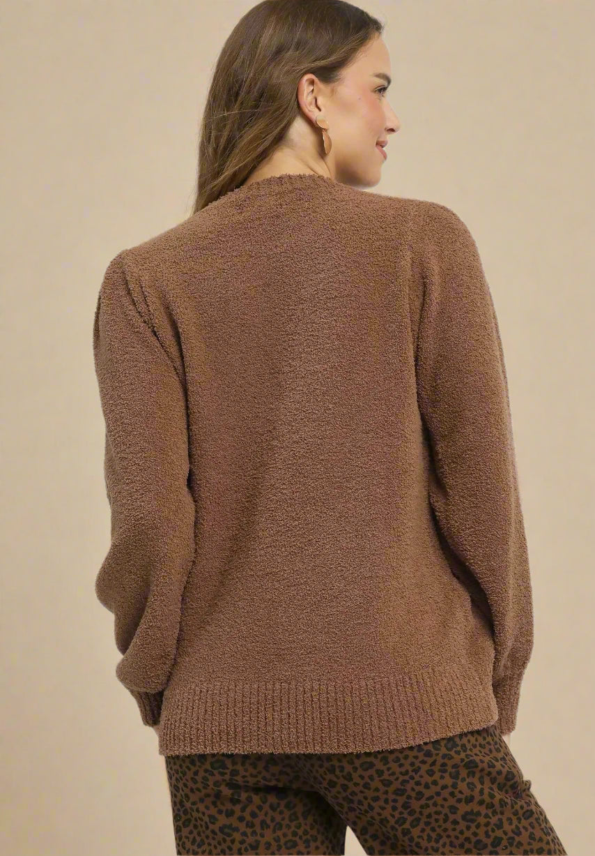 Woman wearing a brown sweater and leopard print pants on a beige background