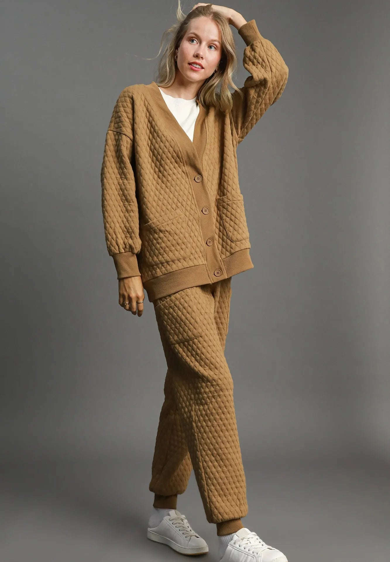 Woman wearing a brown textured outfit with a matching cardigan and pants on a gray background.