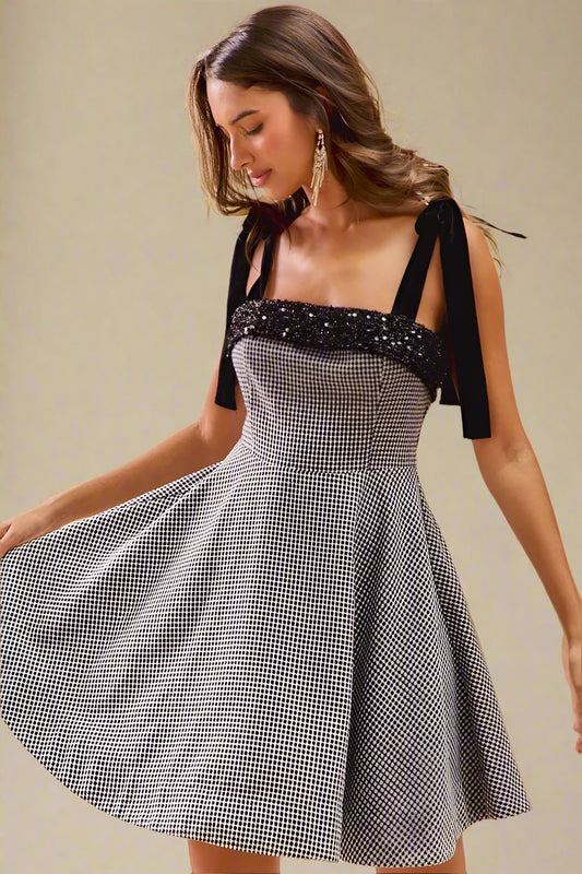 Woman wearing a black and white checkered dress with a bow detail on a beige background