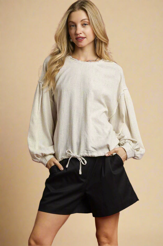 Woman wearing a light-colored blouse and black shorts on a red background