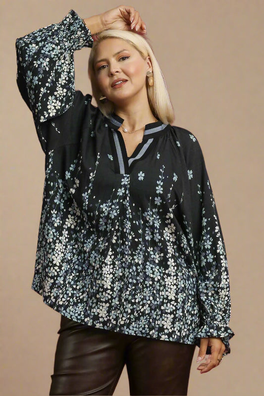 Woman wearing a black floral blouse with brown pants on a beige background