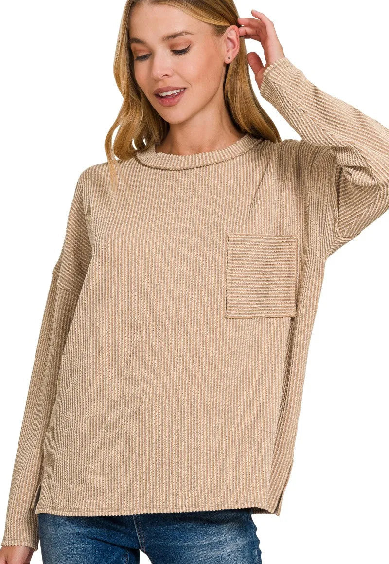 Woman wearing a light brown ribbed sweater with a pocket on a white background