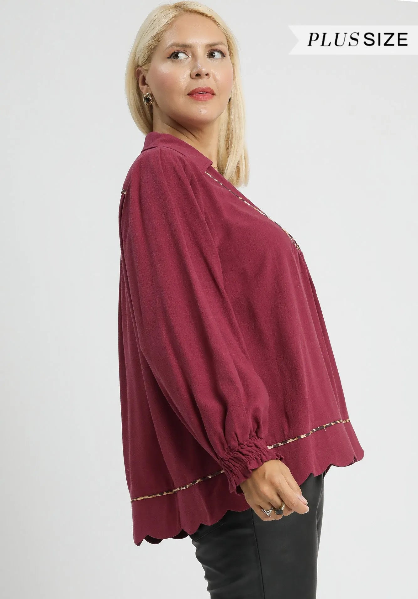 Woman wearing a maroon blouse with gold trim on a white background