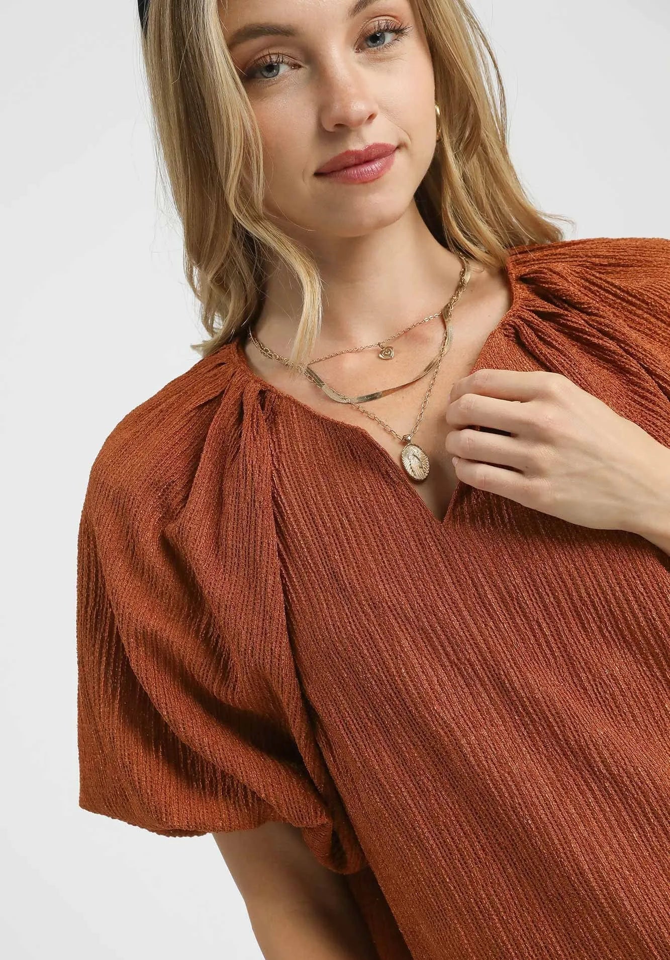 Woman wearing a rust-colored dress with puffed sleeves on a white background