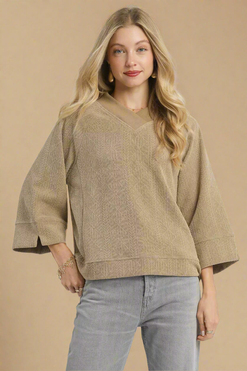 Woman wearing a beige sweater with a plain background