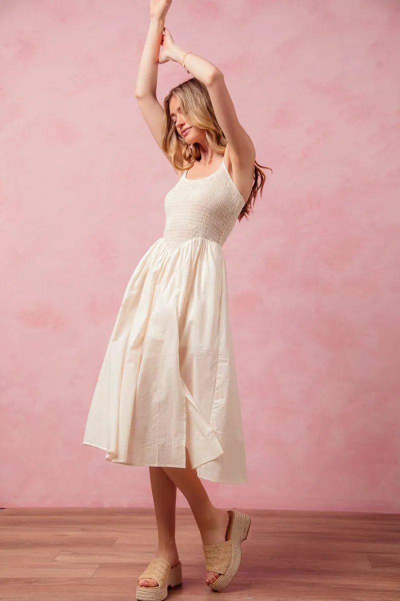 Woman in a white dress posing against a pink wall