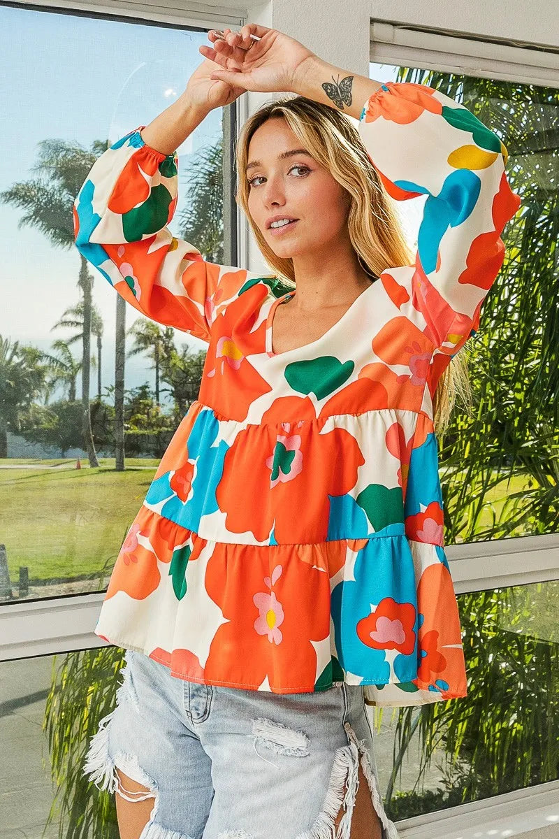 Woman wearing a colorful floral blouse with a blurred outdoor background