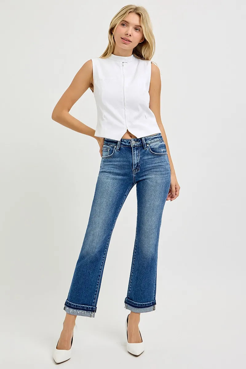 Woman wearing a white sleeveless blouse and blue jeans on a white background