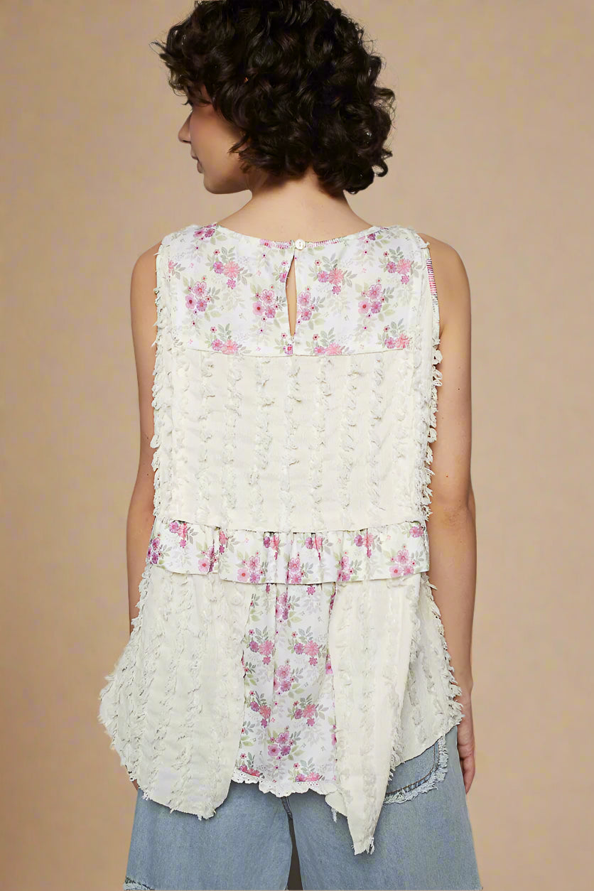 Woman wearing a sleeveless floral top with ruffled layers on a beige background