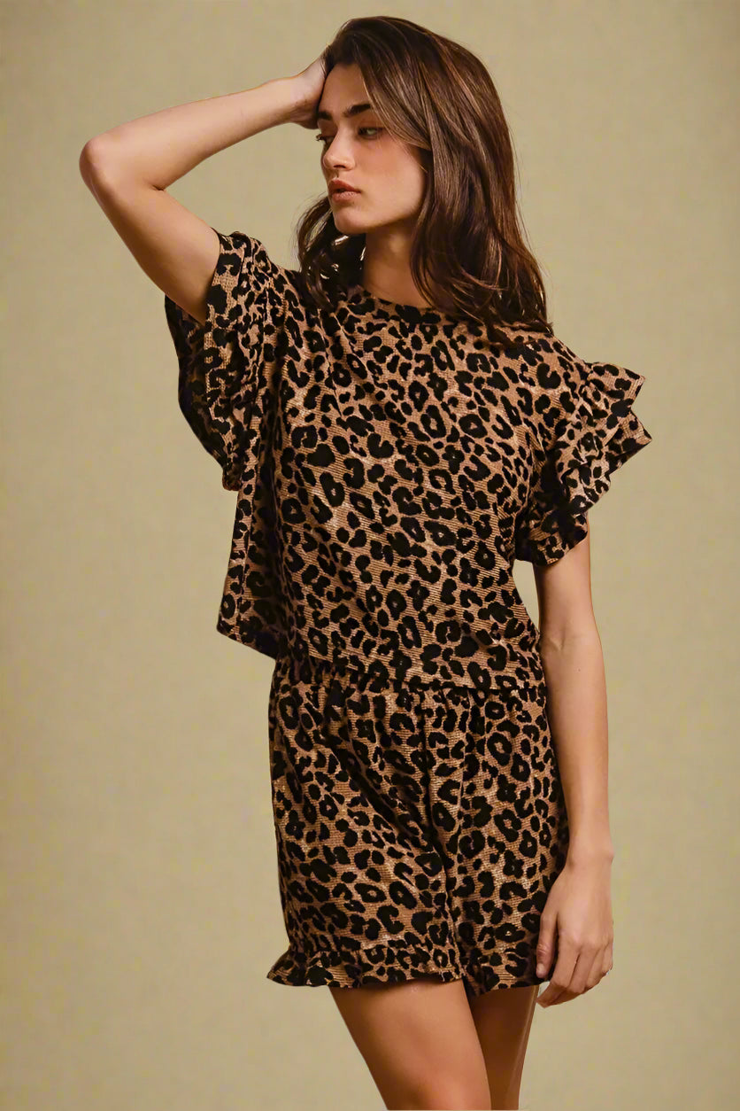 Woman wearing a leopard print shorts set against a beige background