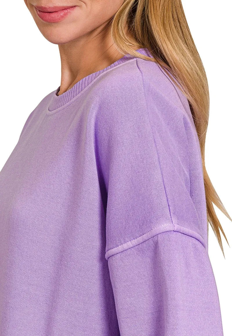 Close-up of a lavender sweater worn by a person with blonde hair.