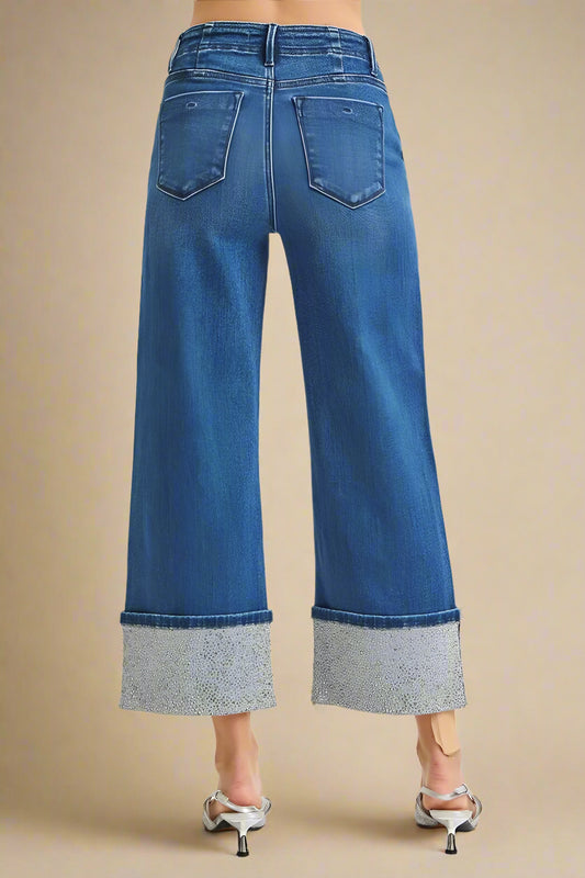 Blue jeans with rhinestone cuffs on a beige background