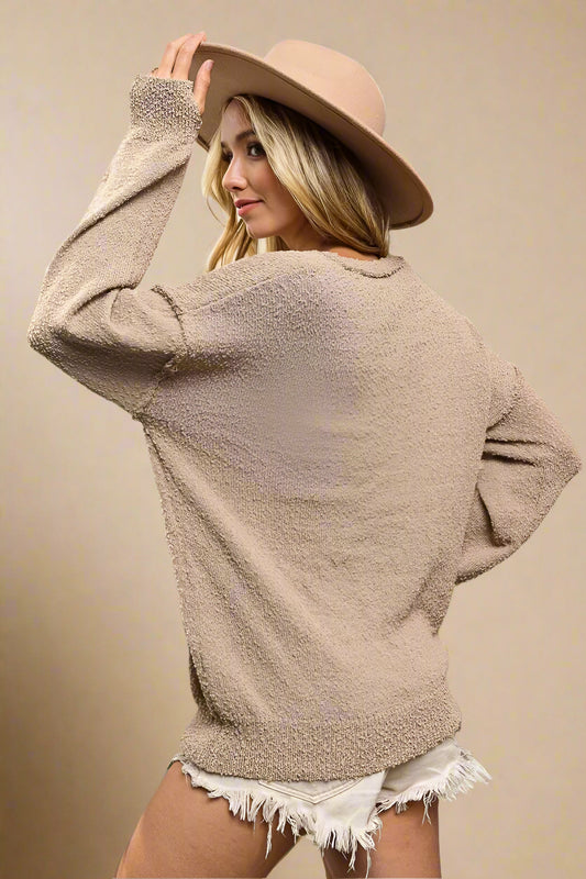 Woman wearing a beige sweater and hat in front of cacti
