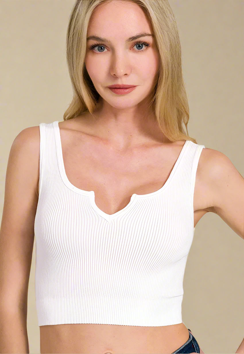 Woman wearing a white tank top against a beige background