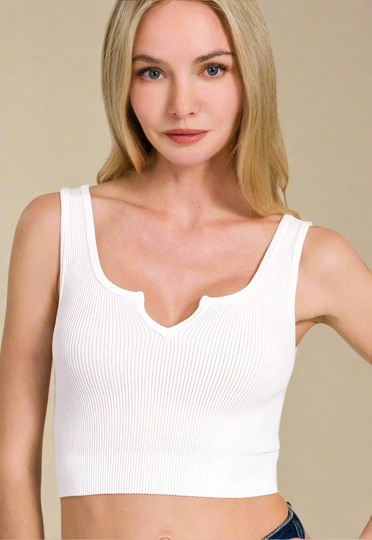 Woman wearing a white tank top against a beige background
