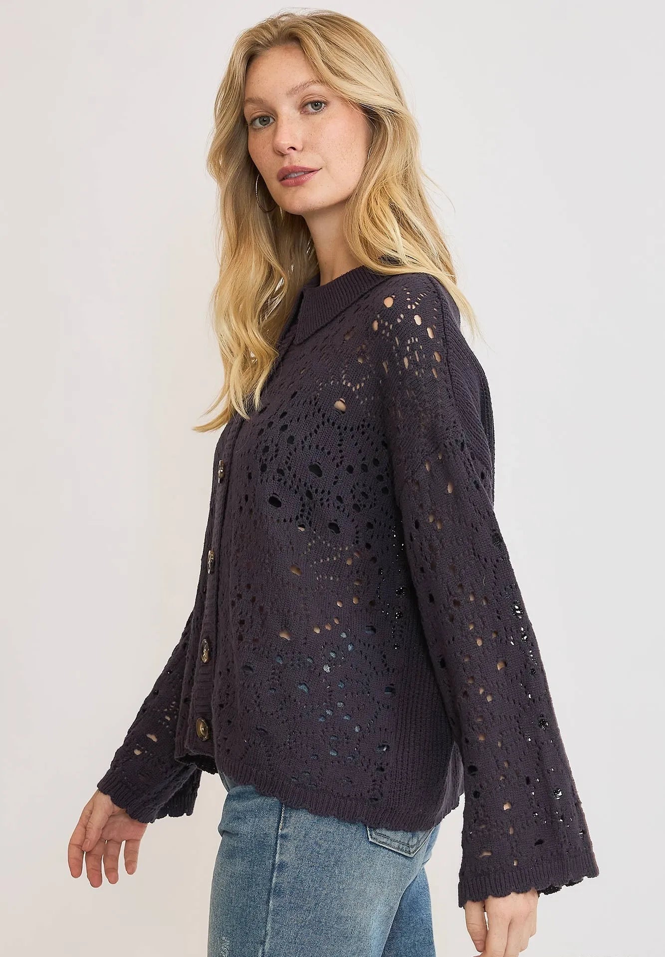 Woman wearing a dark purple knit sweater with a subtle pattern on a plain background