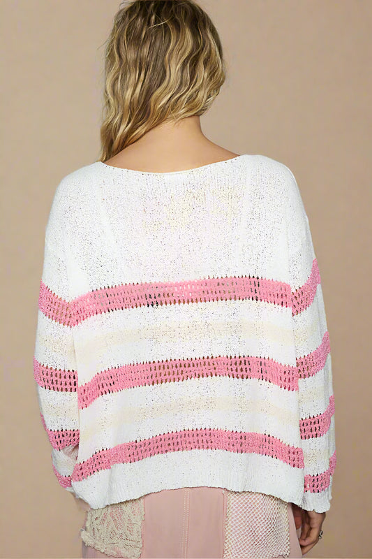 Person wearing a white and pink striped sweater on a plain background