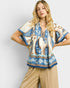 Woman wearing a patterned blouse with a plain background
