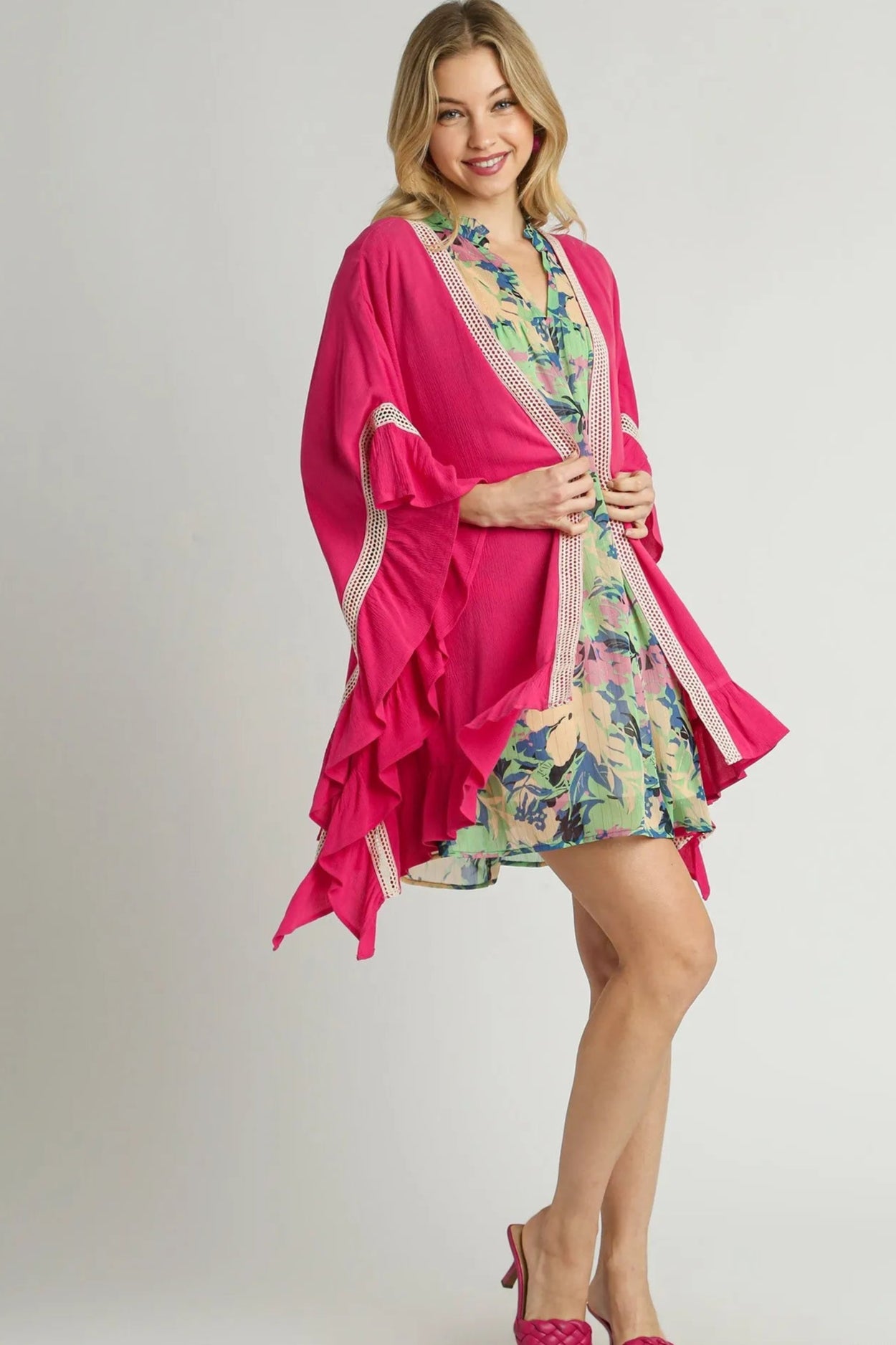 Woman wearing a pink robe over a floral dress on a gray background