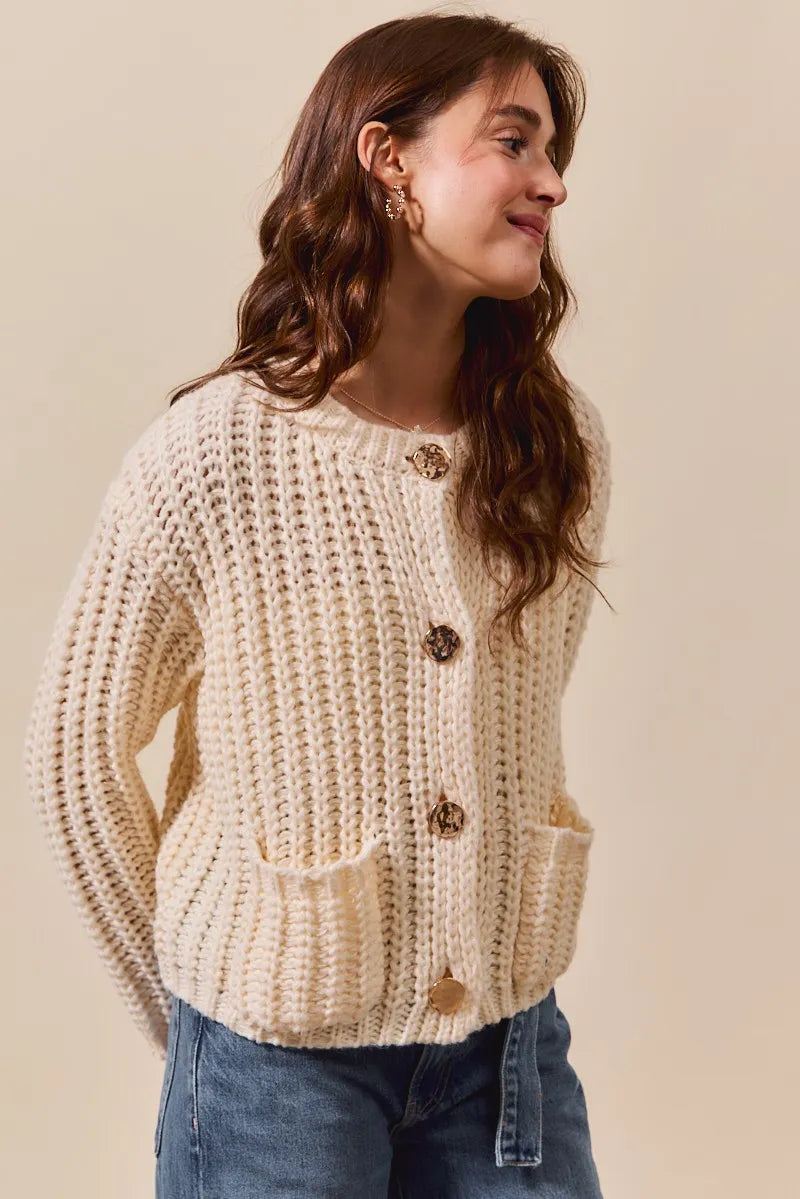 Woman wearing a beige knitted cardigan with buttons on a beige background