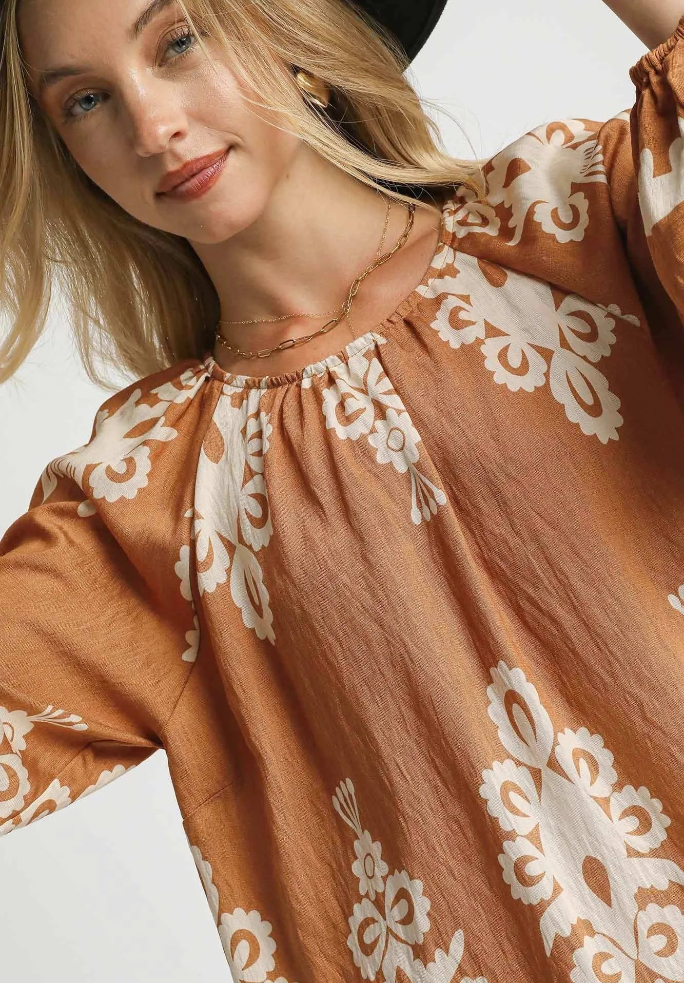 Woman wearing a brown dress with white lace details on a light background