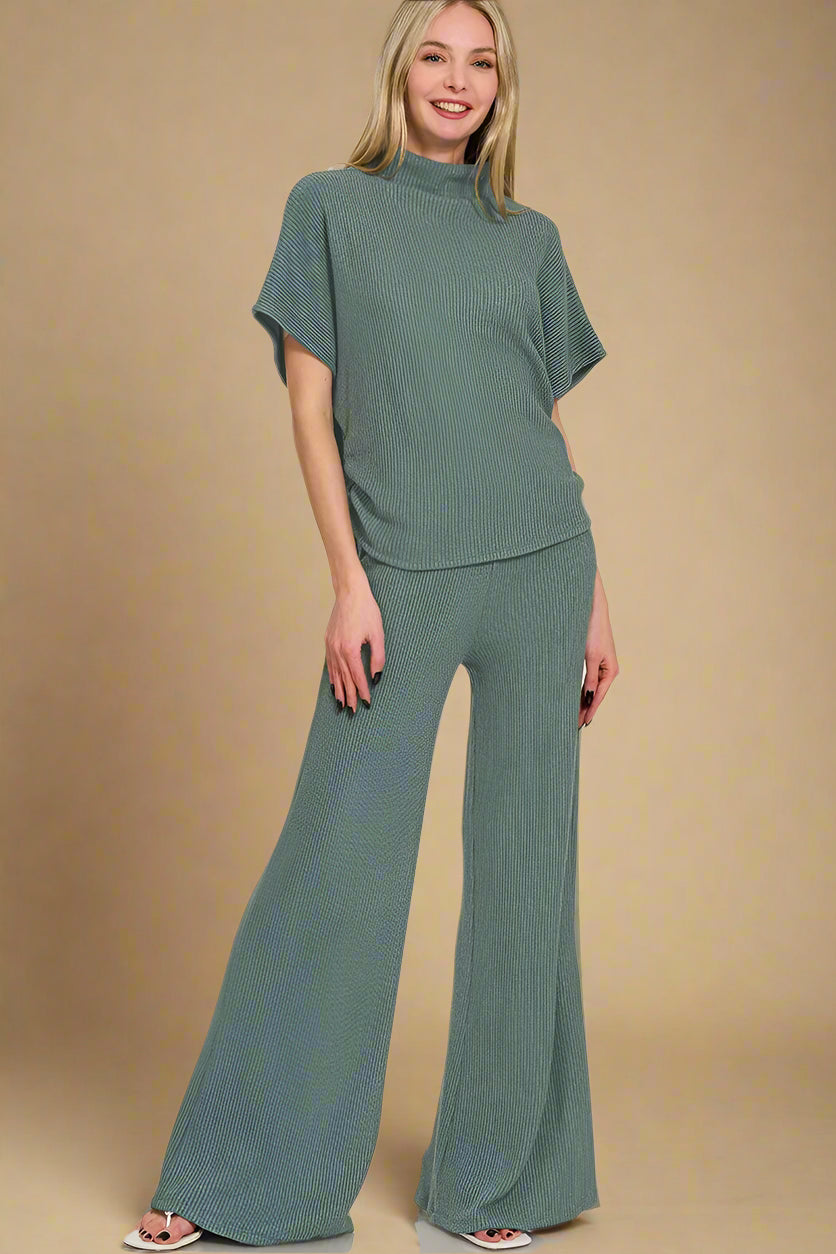 Woman wearing a green outfit with wide-leg pants on a beige background