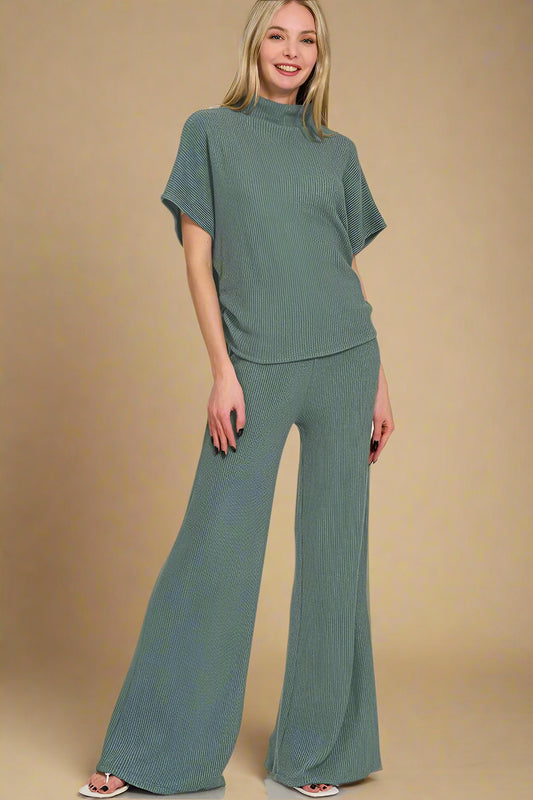 Woman wearing a green outfit with wide-leg pants on a beige background