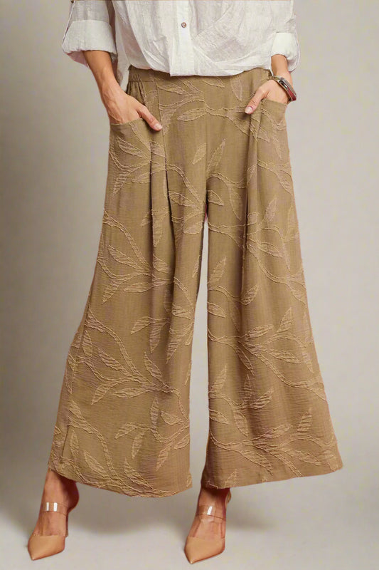 Person wearing beige patterned wide-leg pants on a red background