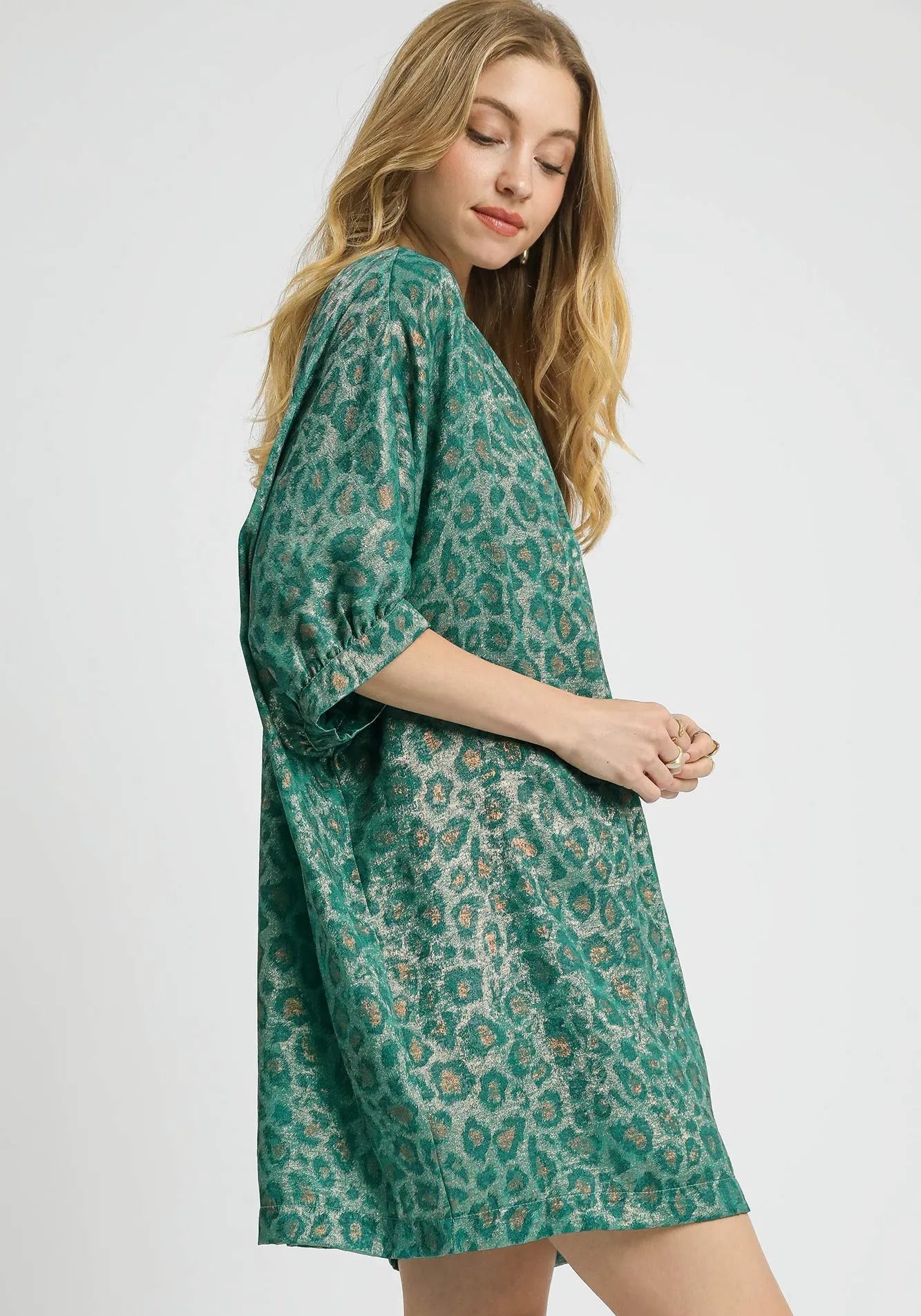 Woman wearing a green patterned dress on a white background