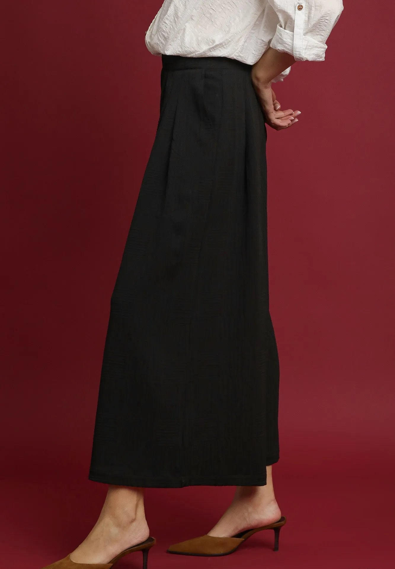 Person wearing black pants with a white blouse on a red background