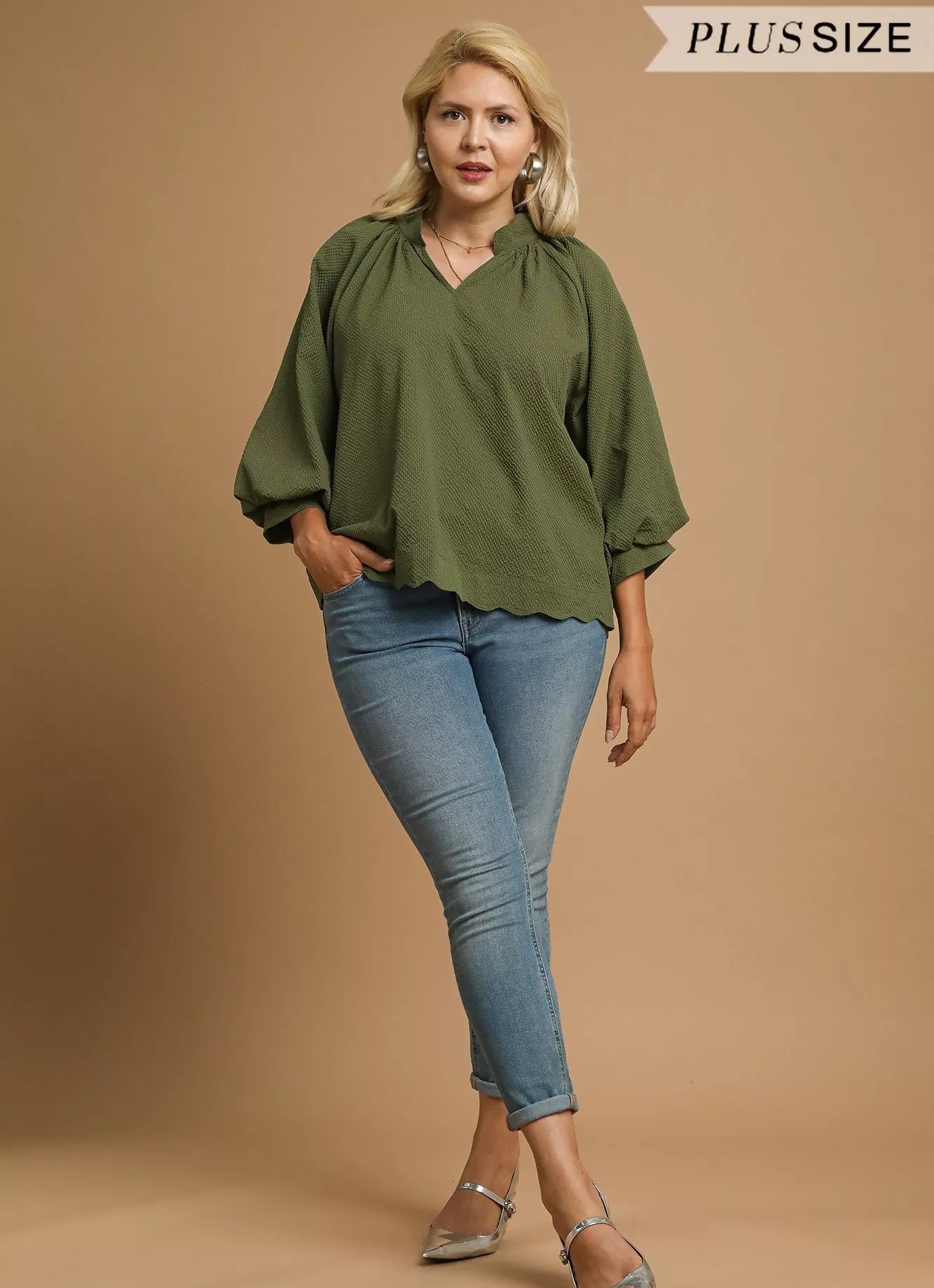 Woman wearing a green blouse and blue jeans on a beige background