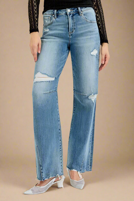 Person wearing distressed blue jeans on a white background