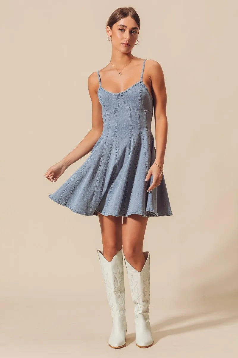 Woman wearing a denim dress with white cowboy boots on a beige background